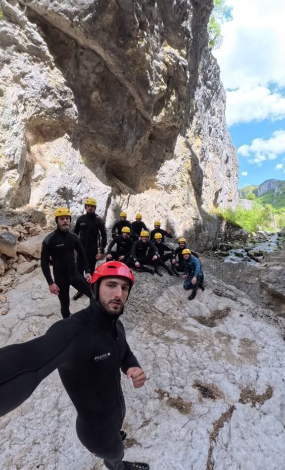 Canyoning group resting on white rock under an overhanging wall in Nevidio
