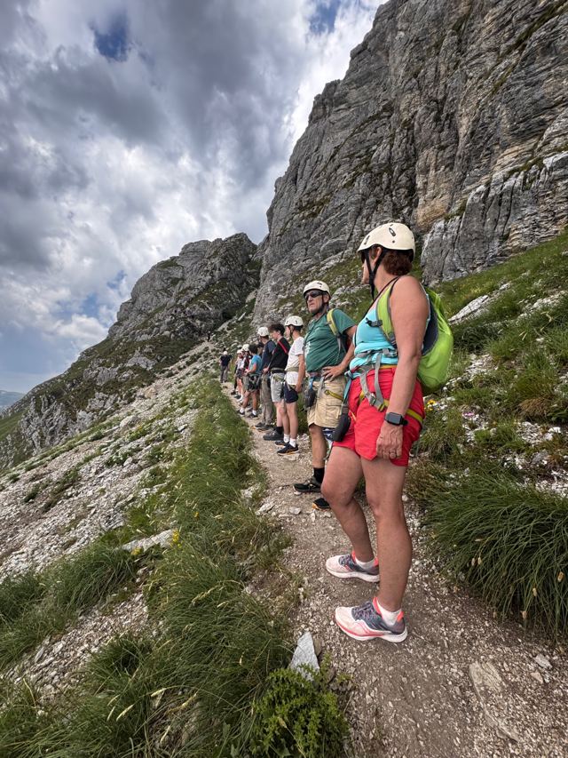 Group with helmets and harnesses on the trail below the via ferrata rock wall
