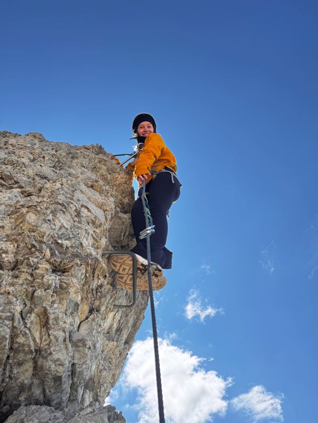 Climber standing on an iron rung against a deep blue sky